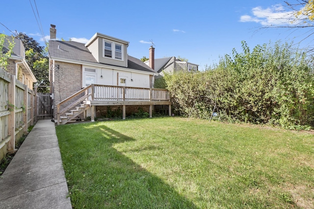 rear view of property with brick siding, fence, a deck, and a lawn