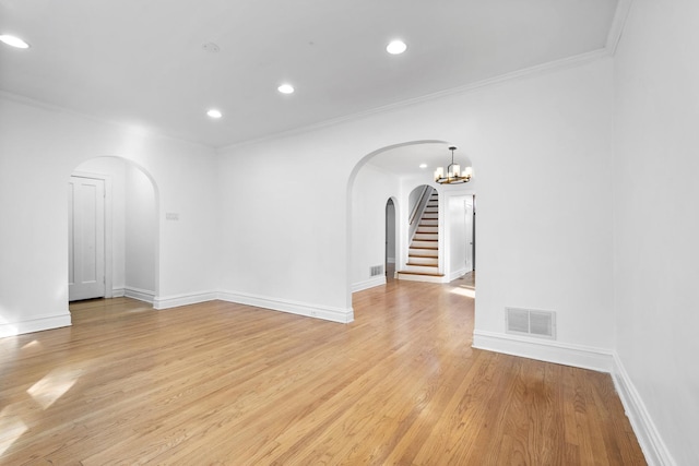 unfurnished room with light wood-style floors, visible vents, arched walkways, and crown molding