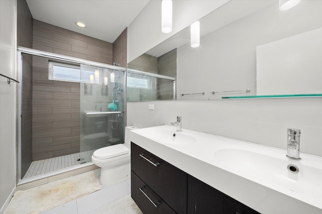 bathroom featuring double vanity, a stall shower, a sink, and toilet