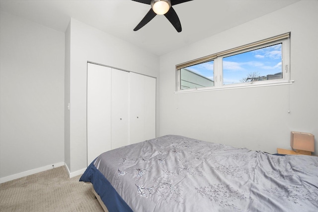 bedroom featuring a ceiling fan, a closet, light carpet, and baseboards