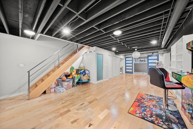 basement featuring baseboards, stairway, and wood finished floors