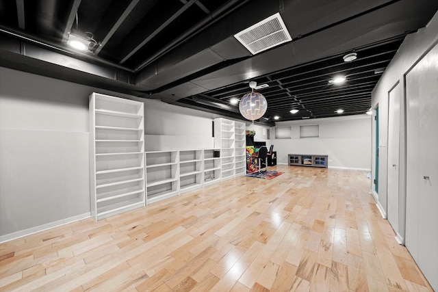 finished basement with visible vents, baseboards, and wood finished floors