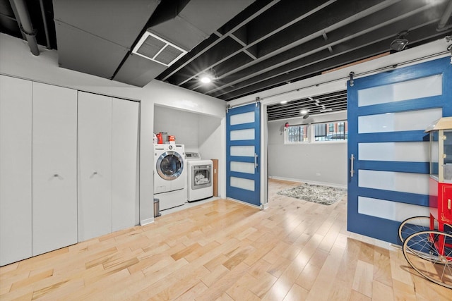 clothes washing area with wood finished floors, visible vents, and washer and dryer