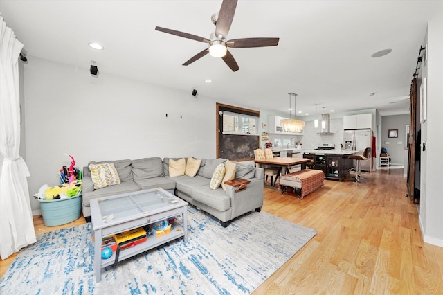 living area with light wood-type flooring, ceiling fan, and recessed lighting