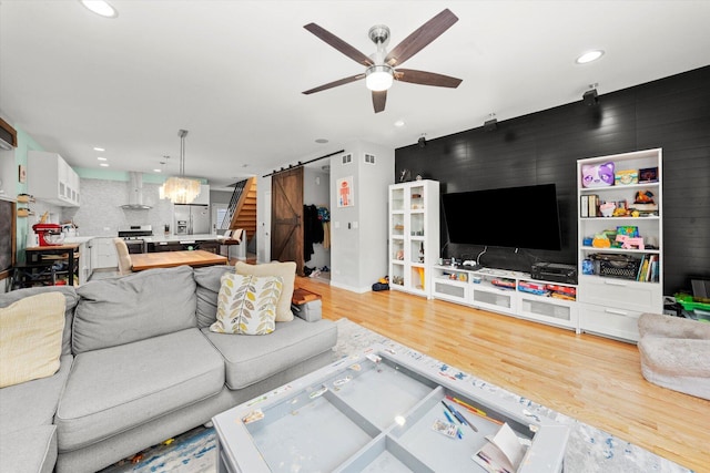 living room with ceiling fan with notable chandelier, recessed lighting, visible vents, wood finished floors, and stairs