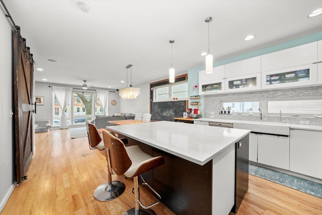 kitchen featuring a barn door, white cabinets, a center island, a sink, and backsplash