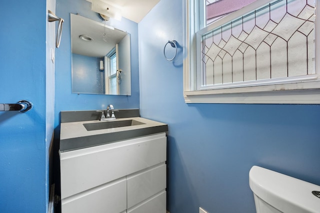 bathroom with a healthy amount of sunlight, vanity, and toilet