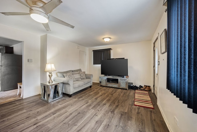 living room featuring ceiling fan, baseboards, and wood finished floors