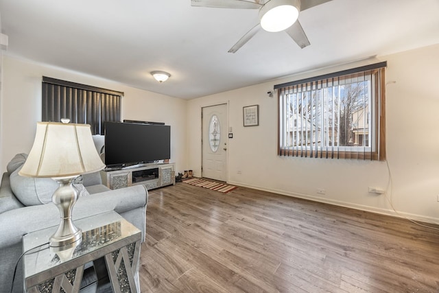 living room with ceiling fan, baseboards, and wood finished floors