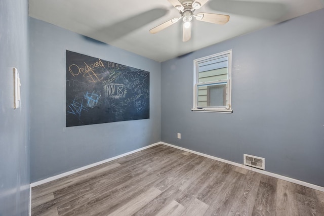 unfurnished room with a ceiling fan, wood finished floors, visible vents, and baseboards