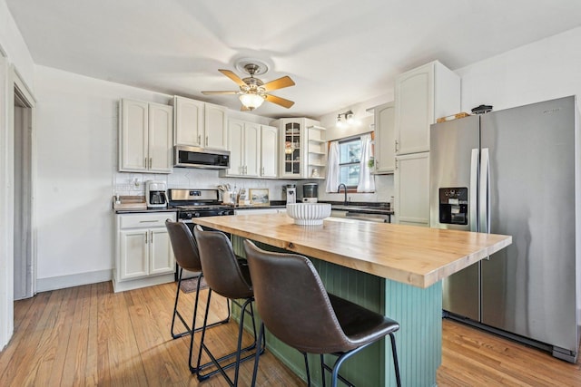 kitchen featuring tasteful backsplash, a kitchen bar, butcher block countertops, and stainless steel appliances