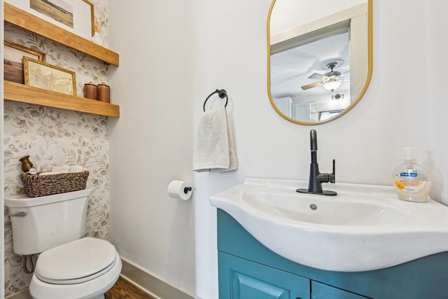 half bathroom featuring baseboards, vanity, toilet, and wood finished floors