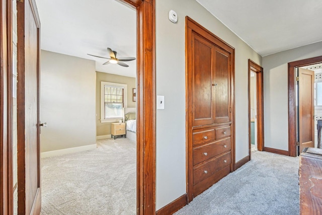 corridor featuring light carpet and baseboards