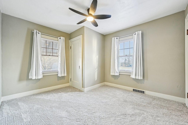 carpeted empty room featuring visible vents, ceiling fan, and baseboards