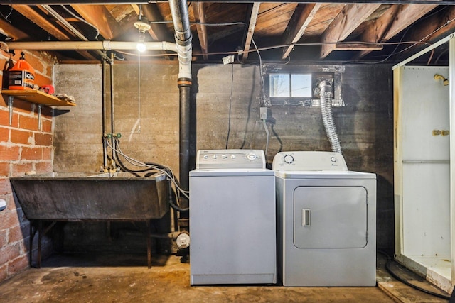 clothes washing area with laundry area, a sink, and washing machine and clothes dryer