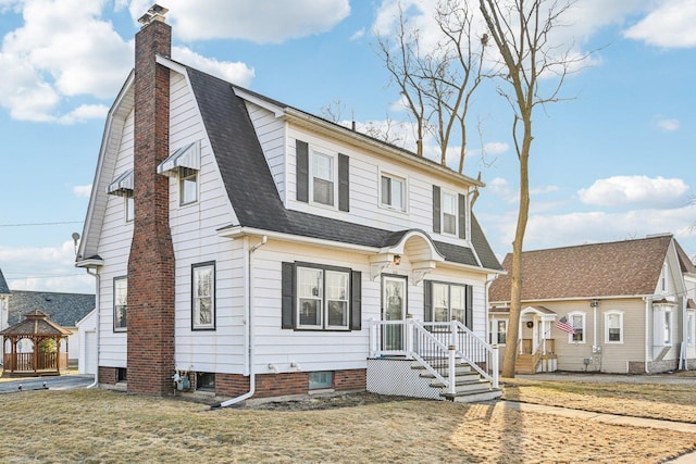 dutch colonial featuring a gazebo, roof with shingles, a chimney, and a gambrel roof