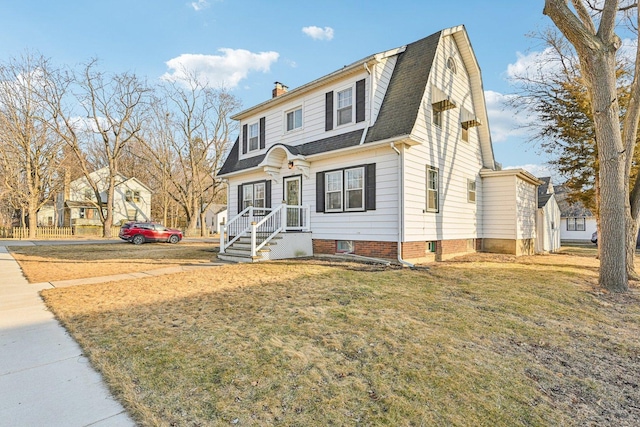 dutch colonial with a chimney, roof with shingles, a front yard, and a gambrel roof