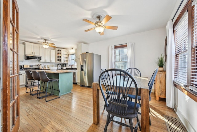 dining area with visible vents, ceiling fan, light wood-style flooring, and baseboards