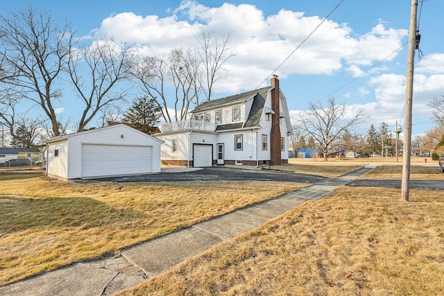 view of front of home with a garage, a gambrel roof, a chimney, an outdoor structure, and a front lawn