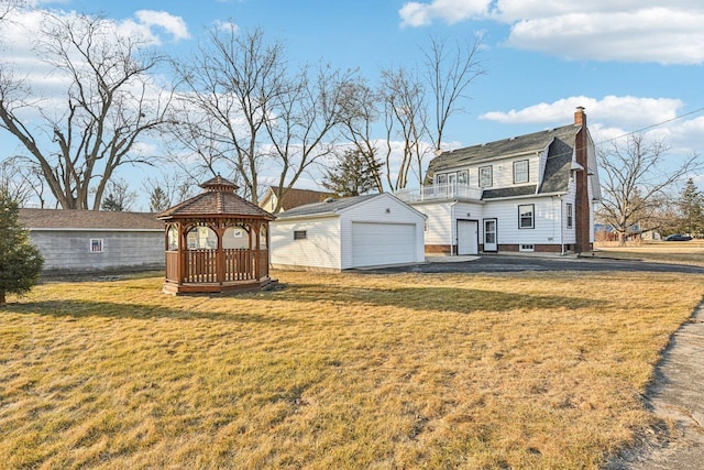 view of front of property featuring an outdoor structure, a detached garage, a gambrel roof, a gazebo, and a front lawn