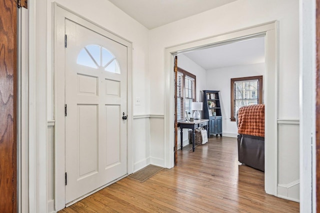 foyer entrance with light wood-style floors, baseboards, and visible vents