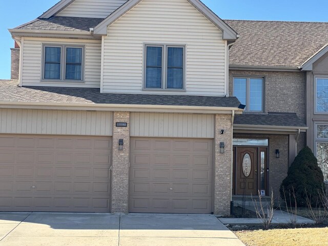 view of front of house featuring a garage, concrete driveway, and roof with shingles