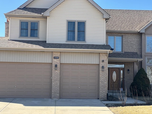 view of front of house with an attached garage, driveway, and a shingled roof