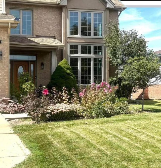 view of home's exterior featuring stucco siding, a lawn, and brick siding