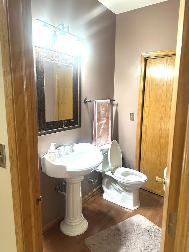 half bath featuring toilet, baseboards, and wood finished floors