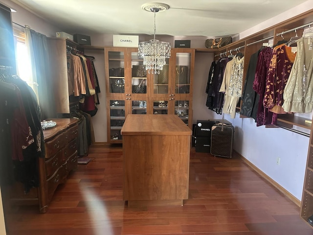 walk in closet featuring dark wood-style flooring and a notable chandelier