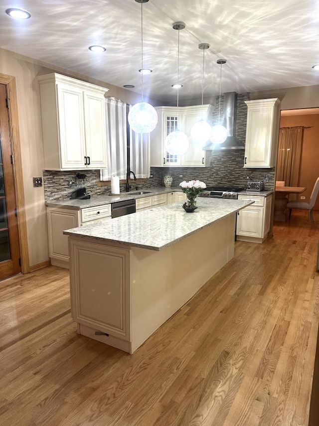 kitchen with black dishwasher, wall chimney range hood, a sink, and light wood-style flooring