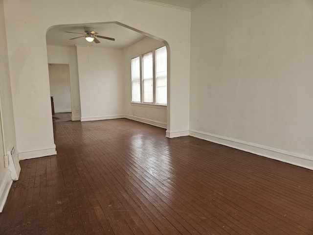 unfurnished room featuring arched walkways, ceiling fan, dark wood-type flooring, and baseboards