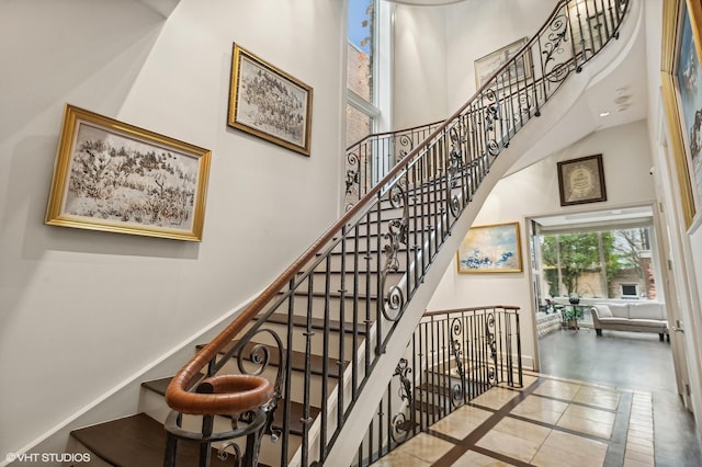 stairs featuring a towering ceiling and baseboards