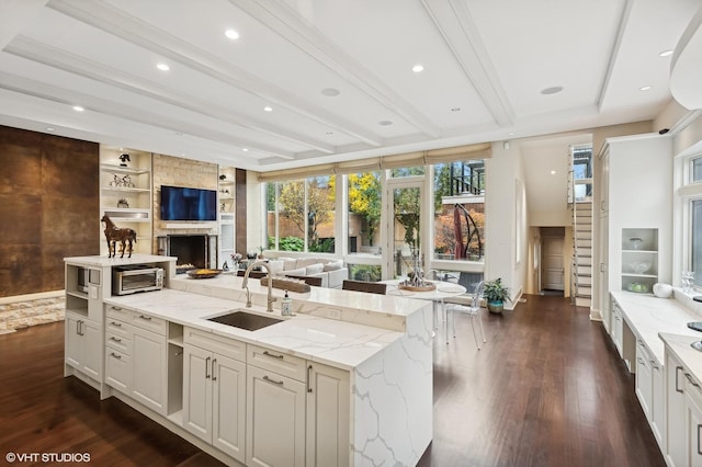 kitchen with dark wood-type flooring, open floor plan, a sink, and beamed ceiling