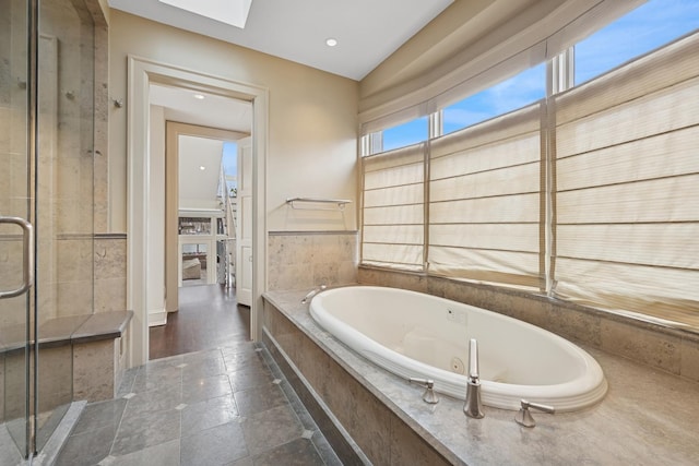 bathroom featuring a skylight, a shower stall, and a tub with jets