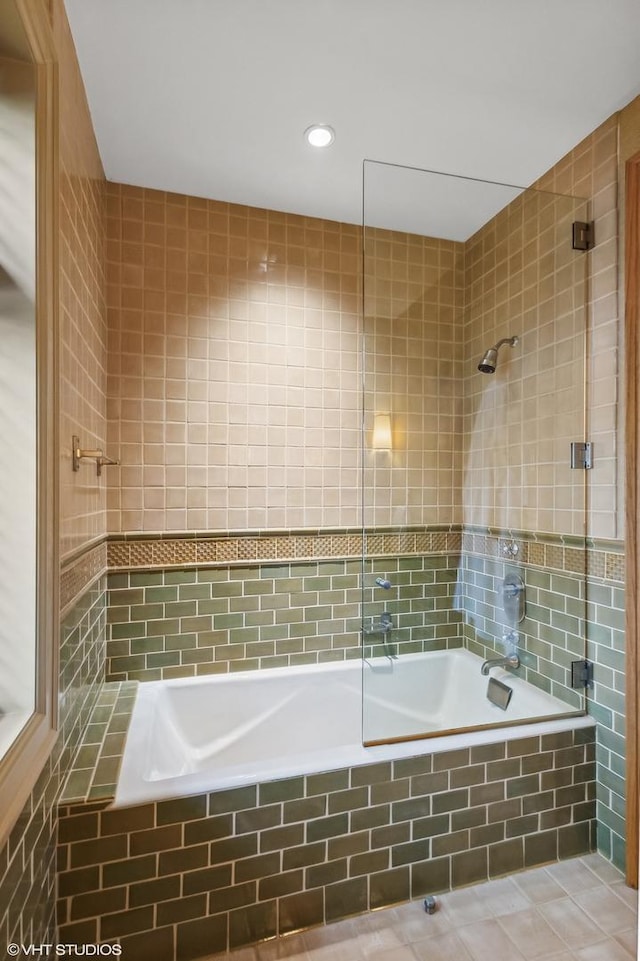 full bath with tiled shower / bath combo, tile patterned flooring, and tile walls