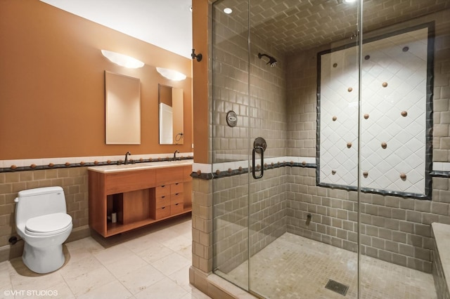 bathroom with a stall shower, a sink, toilet, and double vanity