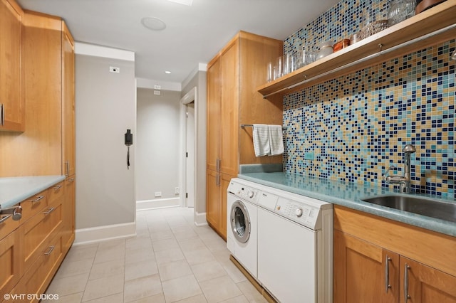 kitchen featuring light tile patterned floors, backsplash, a sink, dishwasher, and baseboards