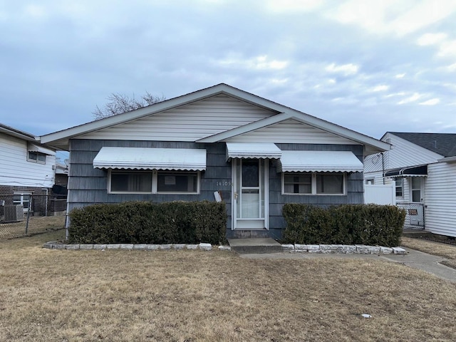 view of front facade with fence, cooling unit, and a front yard