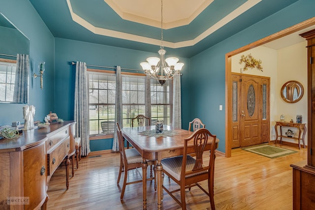 dining space featuring baseboards, light wood-style flooring, a tray ceiling, and a notable chandelier