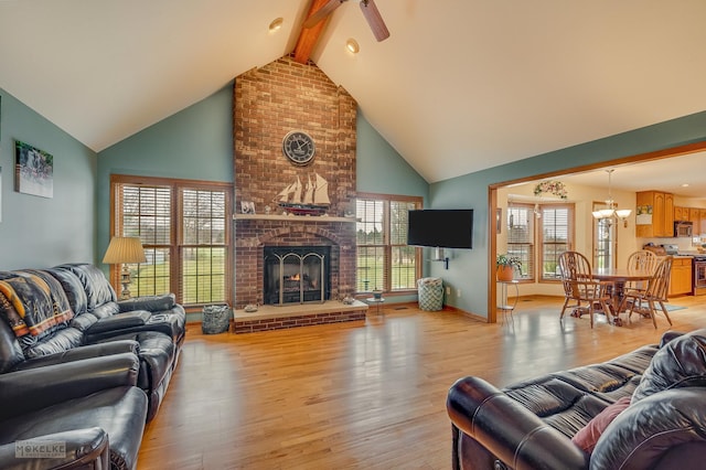 living room with light wood-style floors, beam ceiling, a fireplace, and high vaulted ceiling