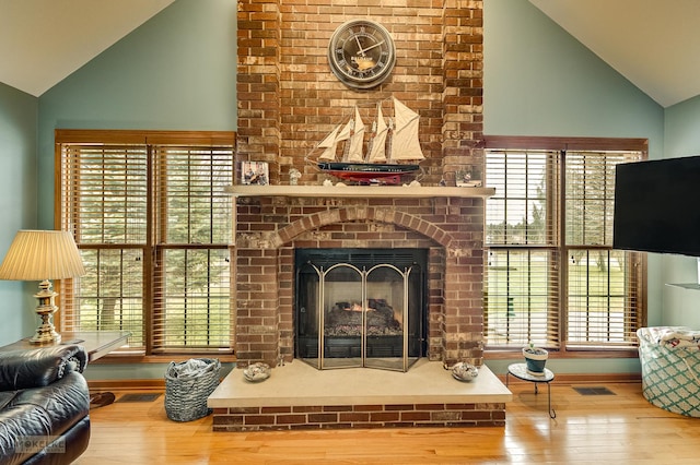 living room with visible vents, a fireplace, baseboards, and hardwood / wood-style flooring