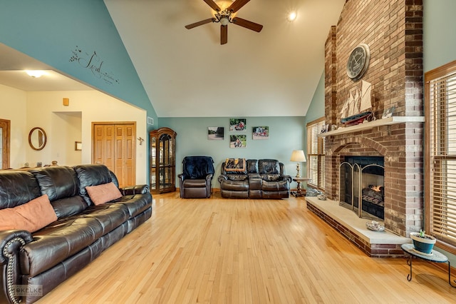 living room featuring a ceiling fan, hardwood / wood-style floors, a healthy amount of sunlight, a fireplace, and high vaulted ceiling