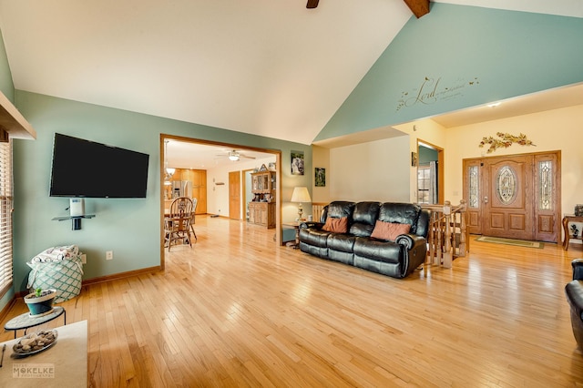 living area featuring ceiling fan, high vaulted ceiling, baseboards, light wood-type flooring, and beam ceiling