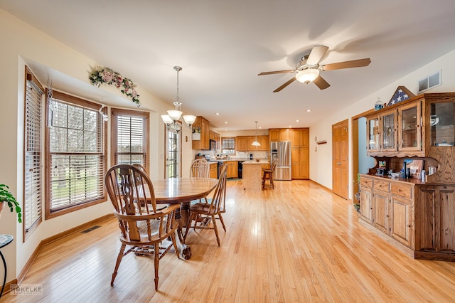 dining room featuring light wood-style floors, baseboards, visible vents, and ceiling fan with notable chandelier