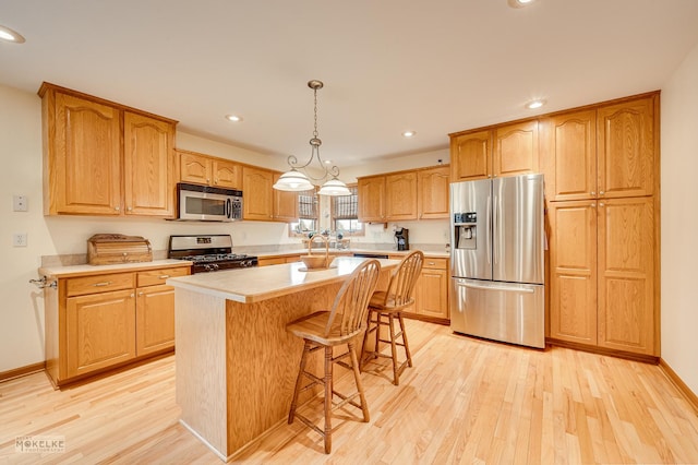 kitchen featuring stainless steel appliances, light wood finished floors, a kitchen bar, and light countertops