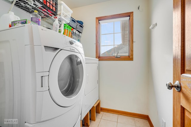 laundry area with light tile patterned floors, laundry area, washer and clothes dryer, and baseboards