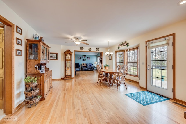 dining room featuring baseboards, ceiling fan with notable chandelier, visible vents, and light wood-style floors