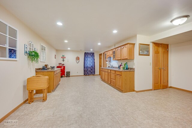 kitchen with recessed lighting, a sink, baseboards, and light stone countertops