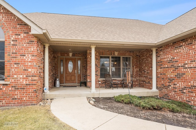 doorway to property featuring brick siding and a shingled roof